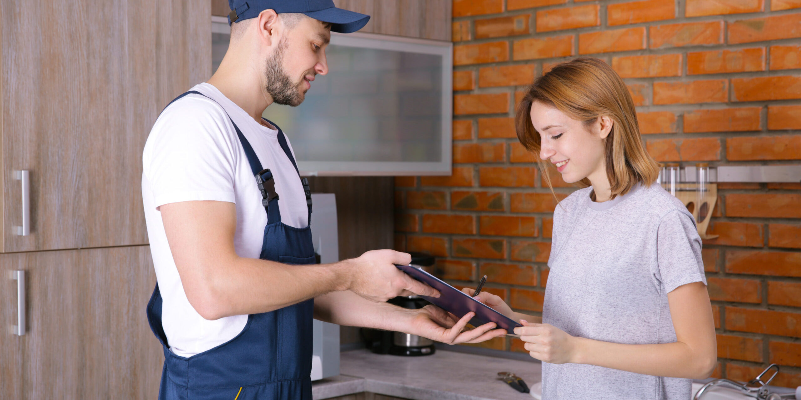 Woman signing receipt for plumber service at home
