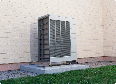 Heat pump on a stand against the wall of a house.