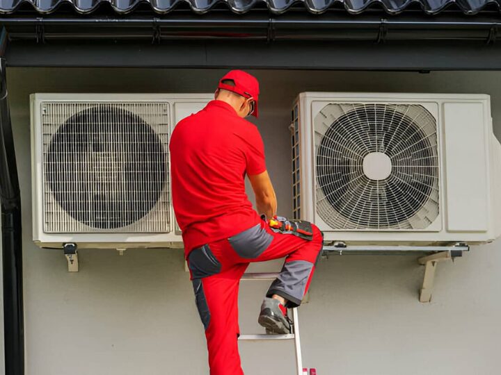 Man on latter repairing heat pump