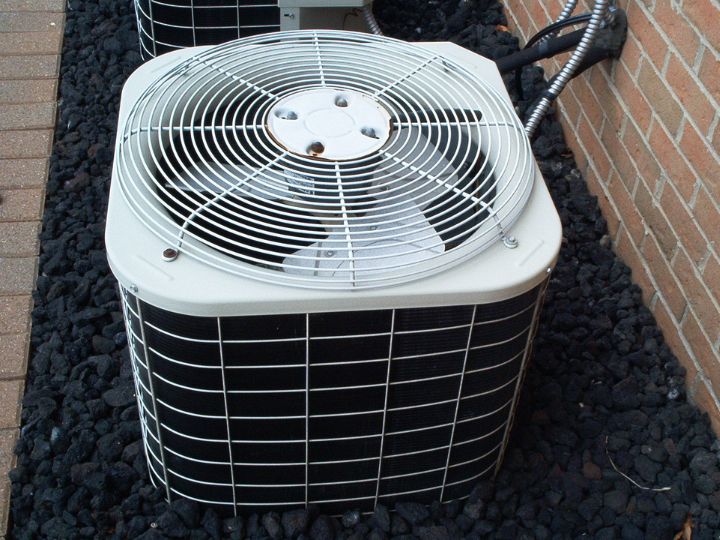 High angle showing the top and side of a new air conditioner unit outside a house.