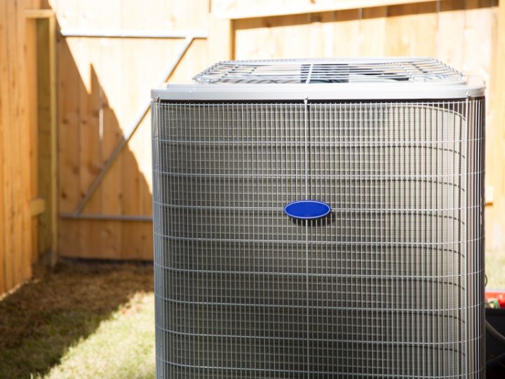 An air conditioning unit standing outside in a backyard.