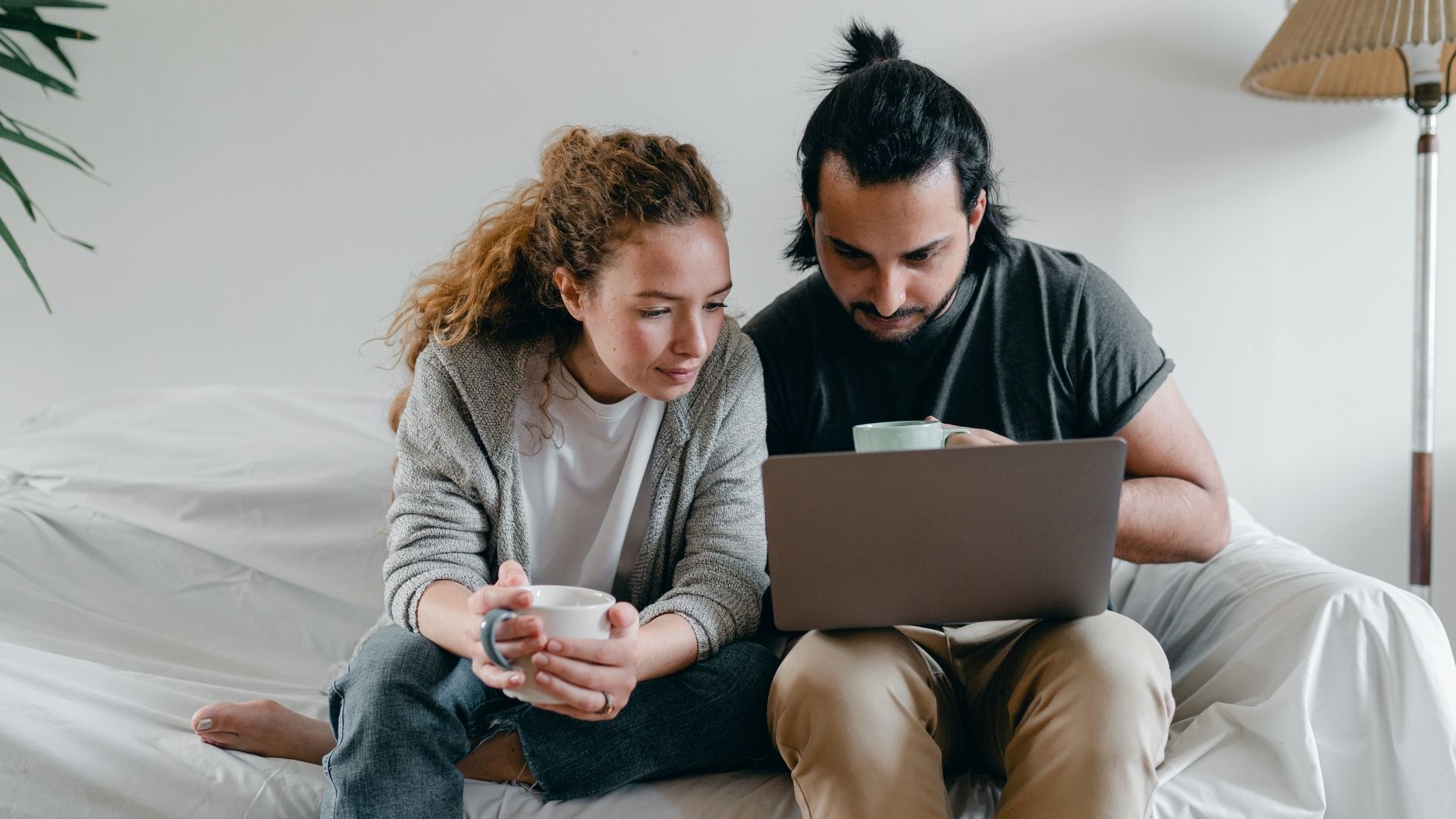 Couple looking at a laptop screen while sitting on couch