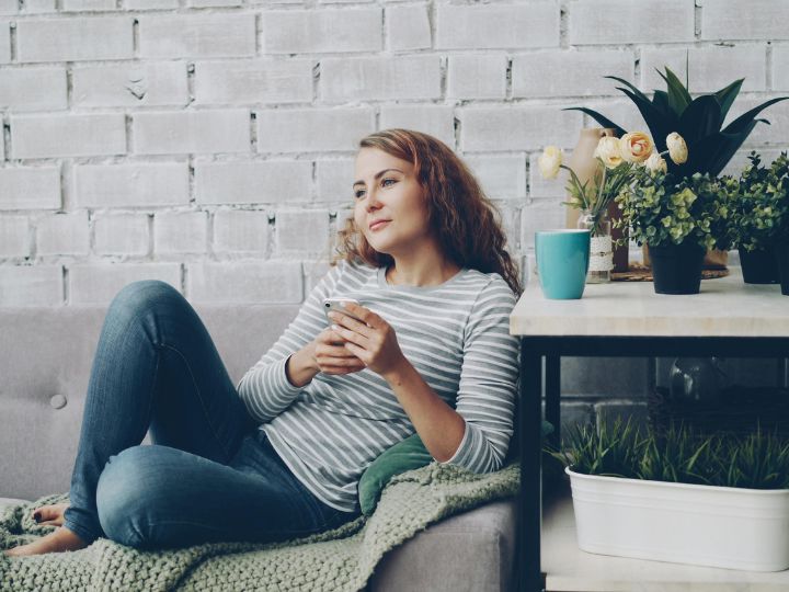 Woman sitting on couch with phone in her hand.