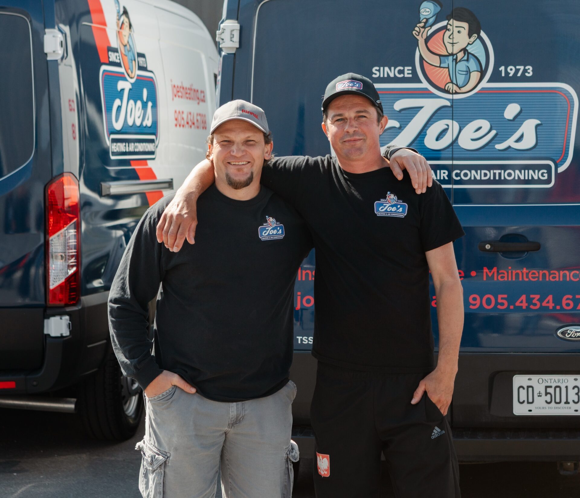 Joe's Heating technicians smiling and standing in front of company truck