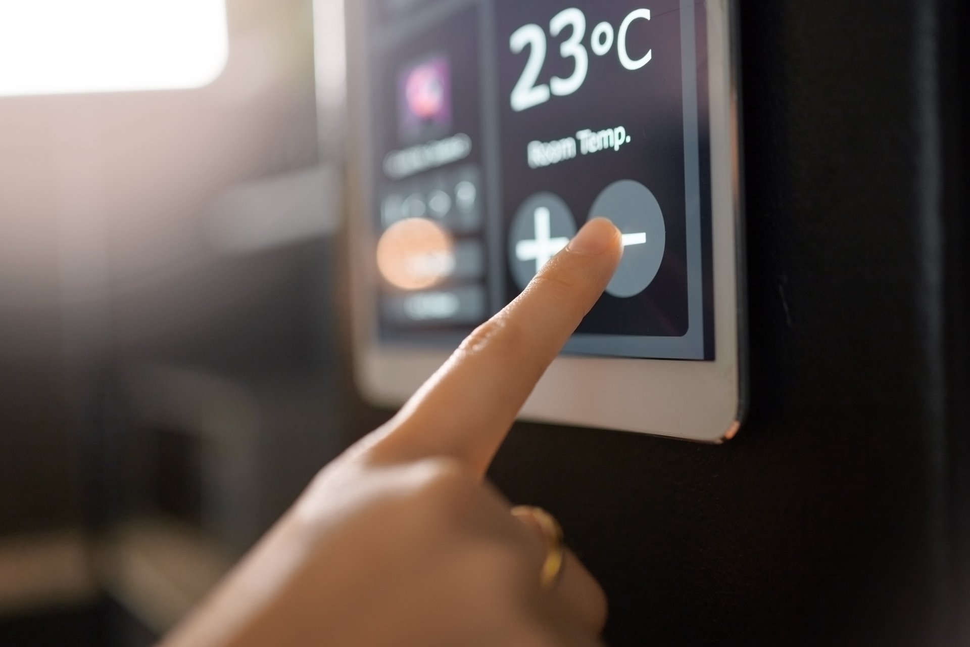 Close-up of finger turning down temperature on a digital thermostat.
