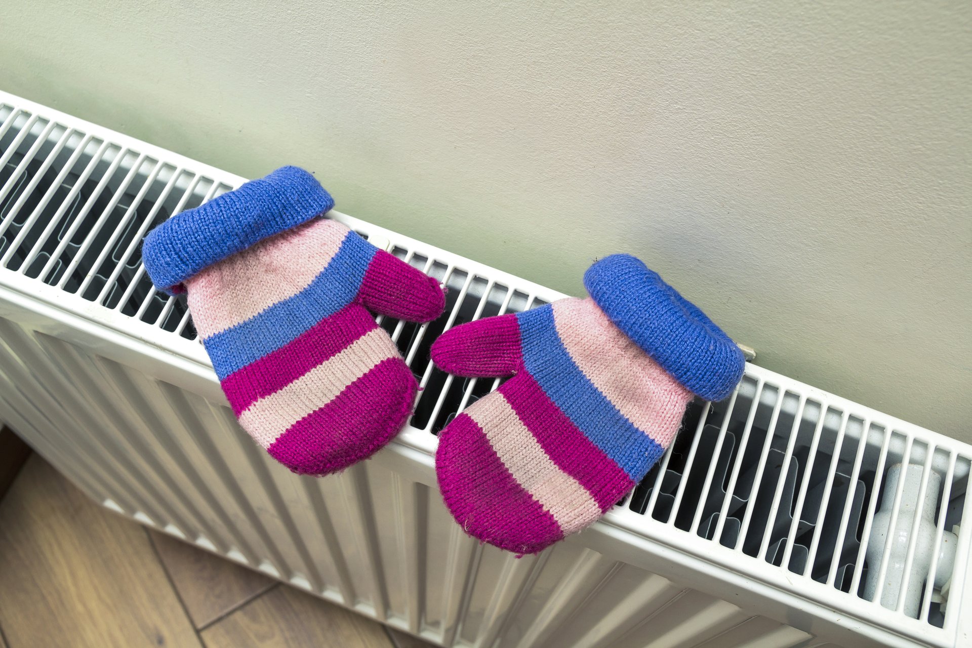 Pair of mittens on top of a furnace.