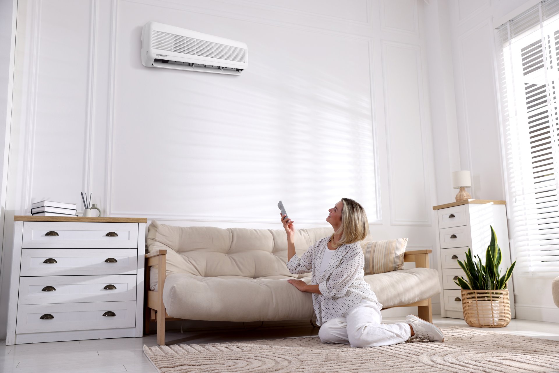 Woman using remote control to turn on ductless air conditioning